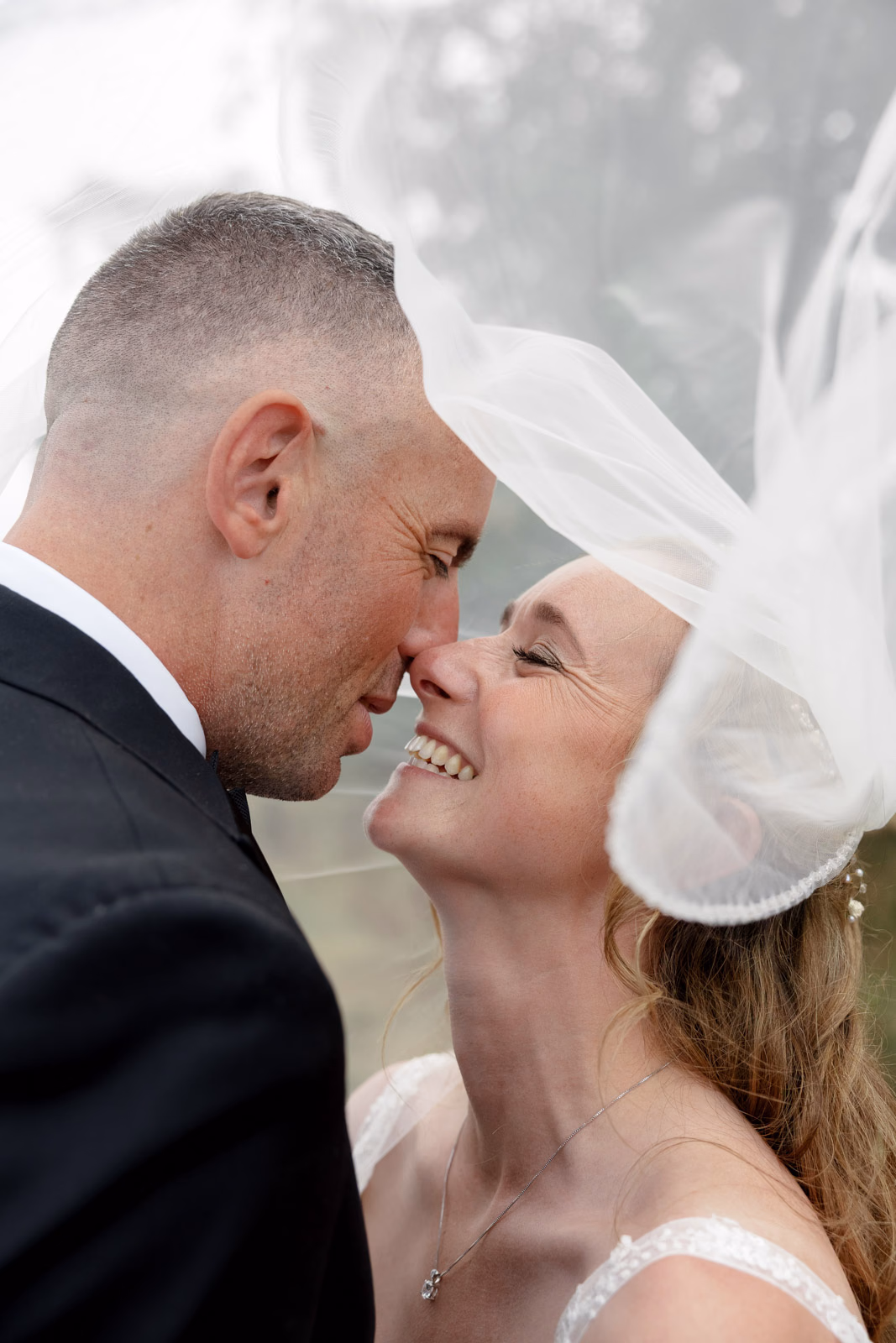 Bride and groom veil blowing intimate moment at a family farm wedding in Taunton