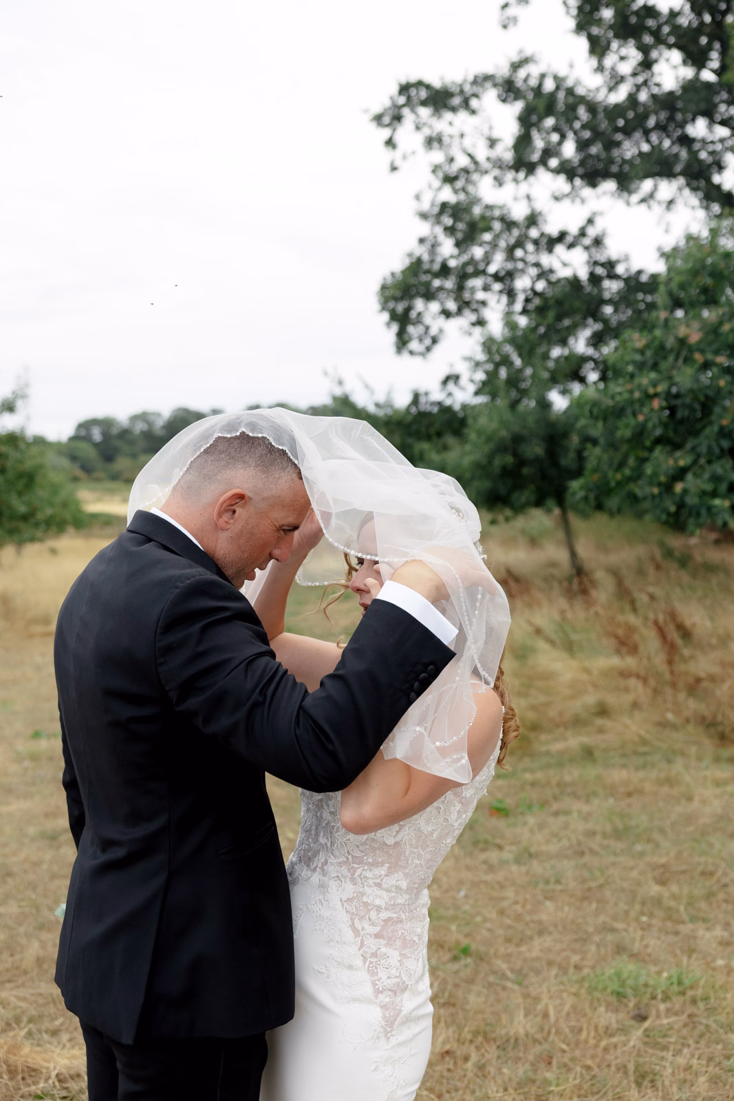 Bride and groom under veil at a Taunton farm wedding, photographed by Tanya Bogdan Photography