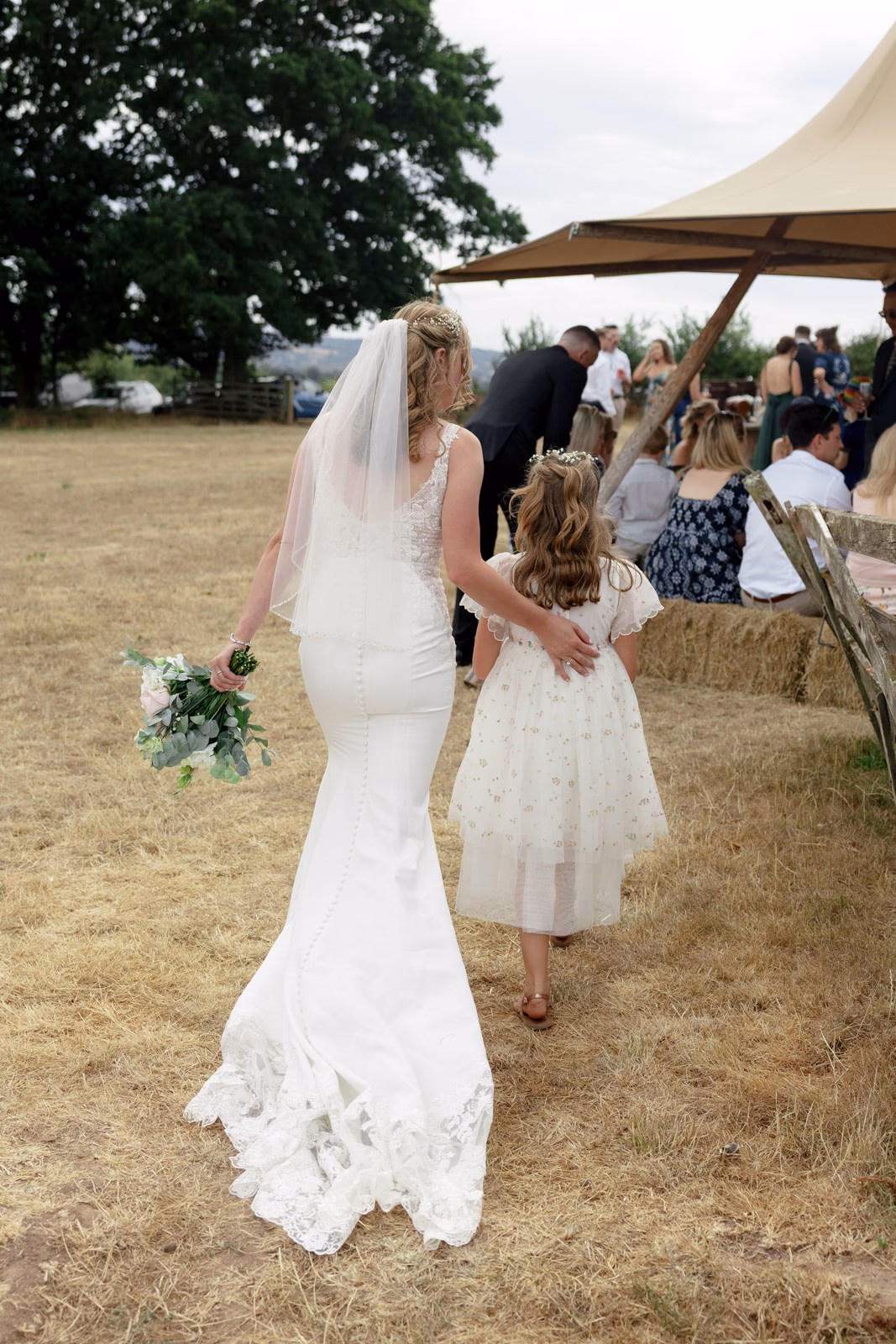 Bride walking with flower girl at a Taunton farm wedding, photographed by Tanya Bogdan Photography