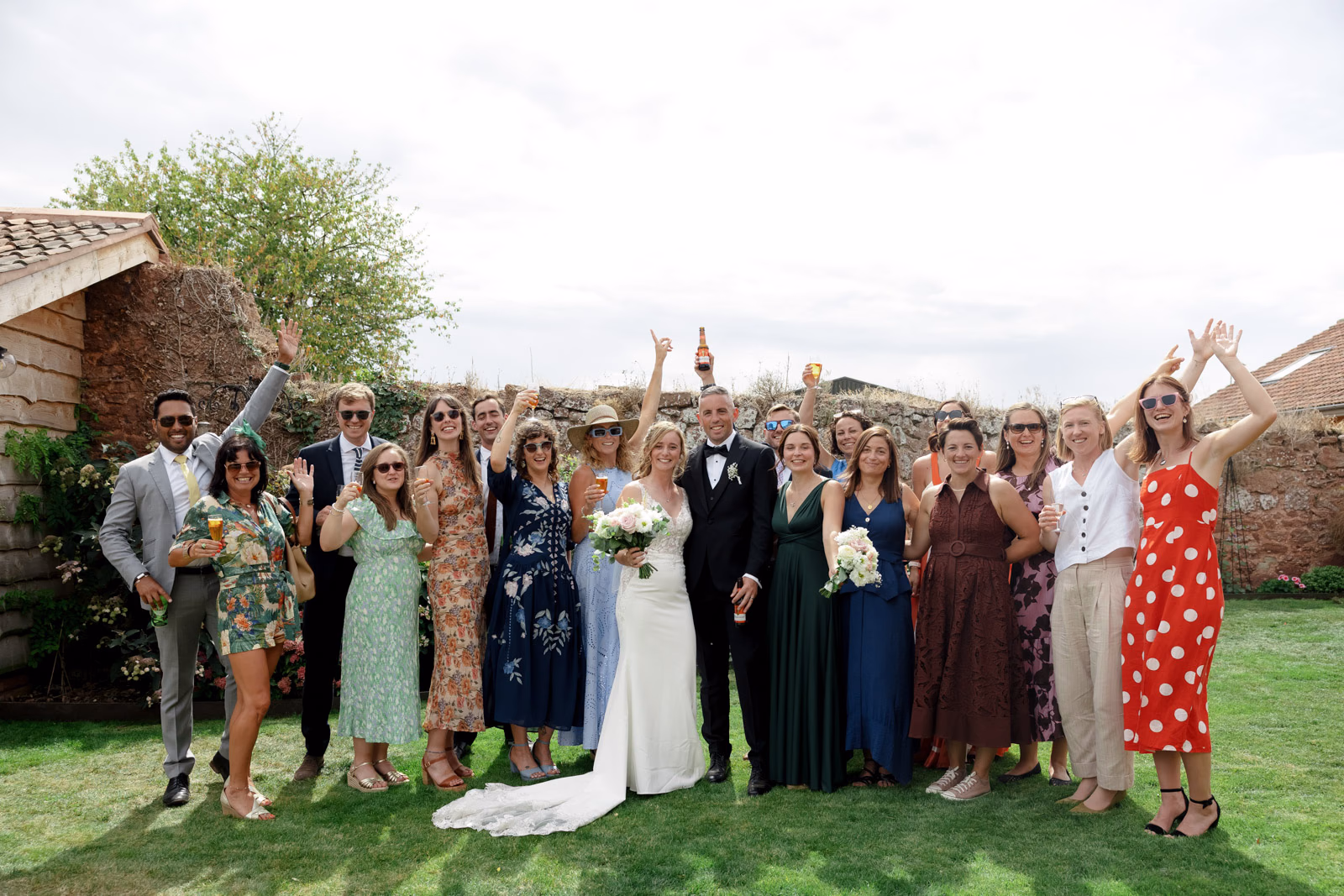 Wedding guests cheering group photo at a Taunton farm wedding, photographed by Tanya Bogdan Photography