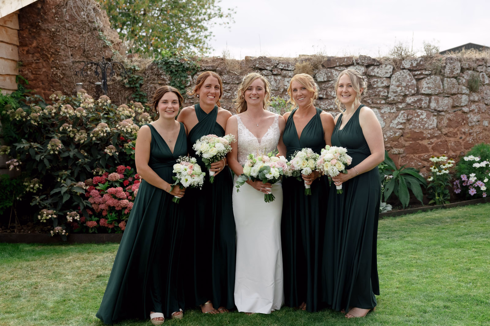 Bride with bridesmaids holding bouquets at a family farm wedding in Taunton