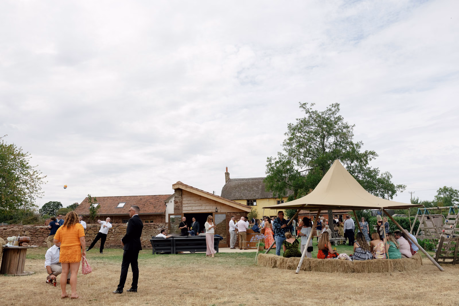 Guests mingling tipi bar farm at a family farm wedding in Taunton