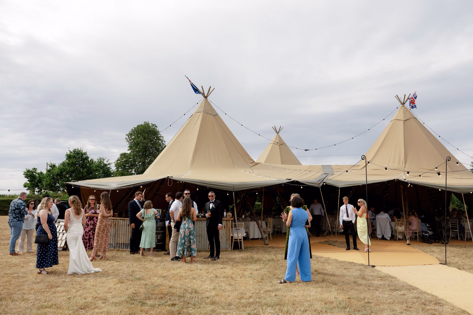 Guests gathering tipi drinks reception at a family farm wedding in Taunton