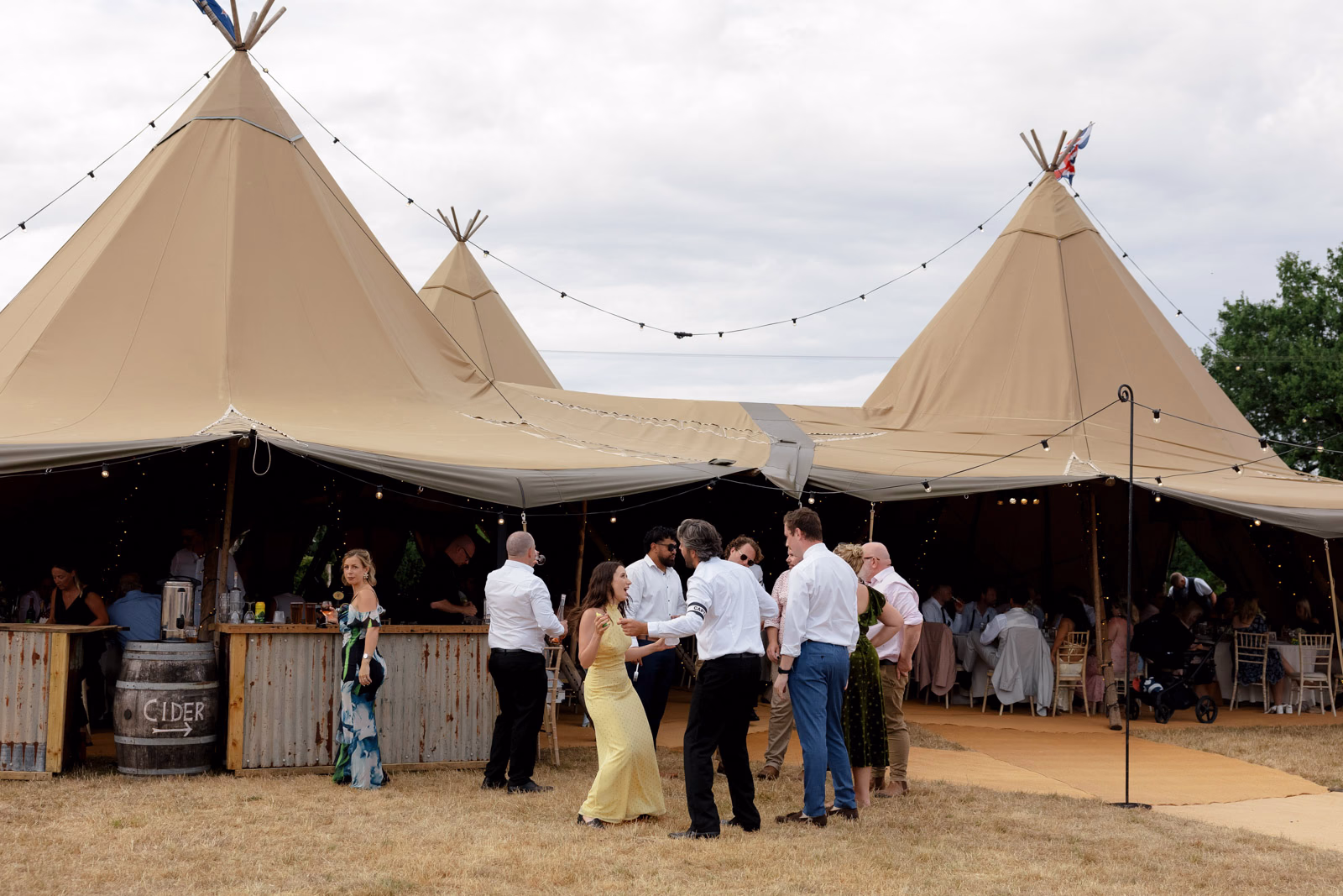 Guests outside tipi bar at a family farm wedding in Taunton
