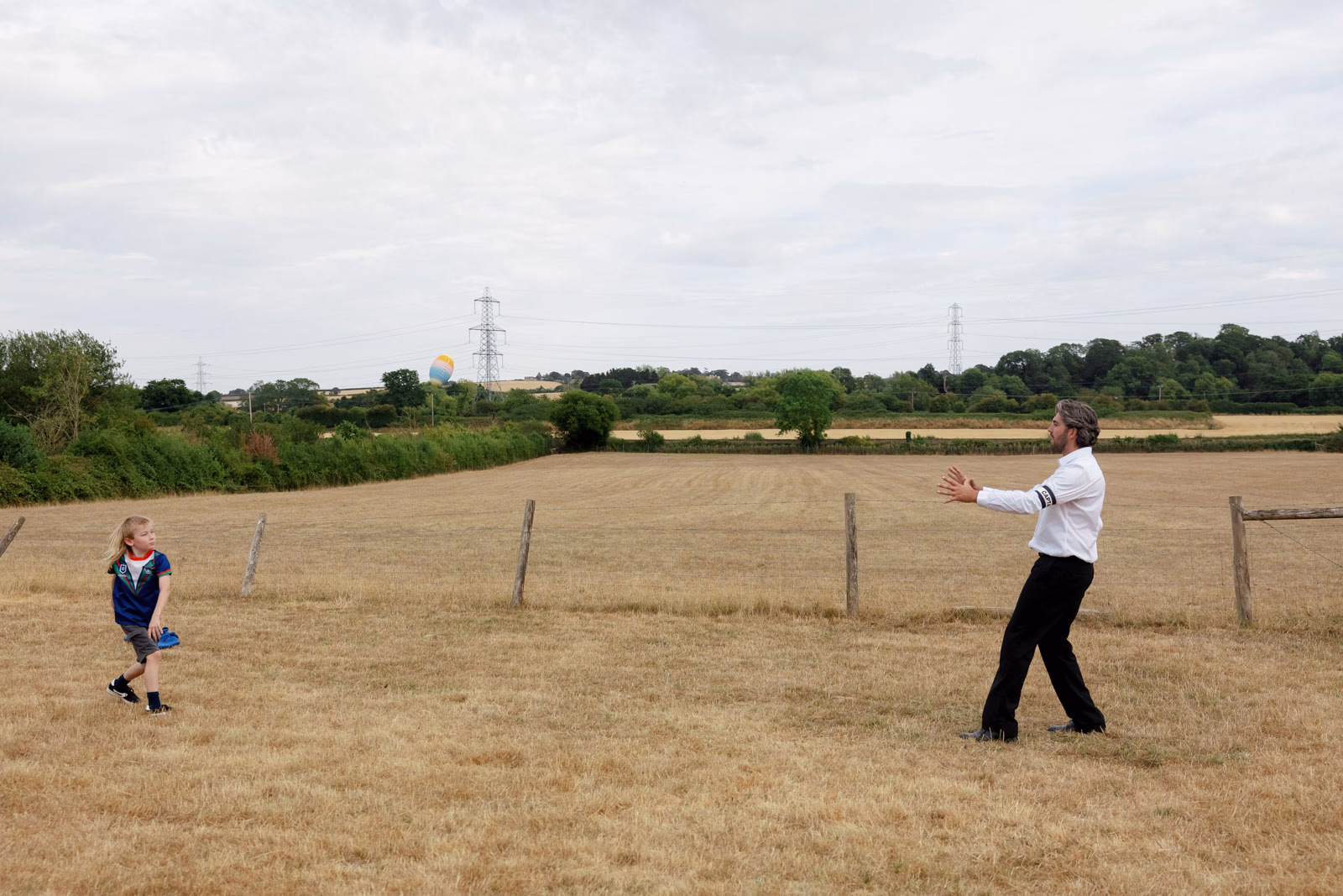 Child and guest playing in field at a family farm wedding in Taunton