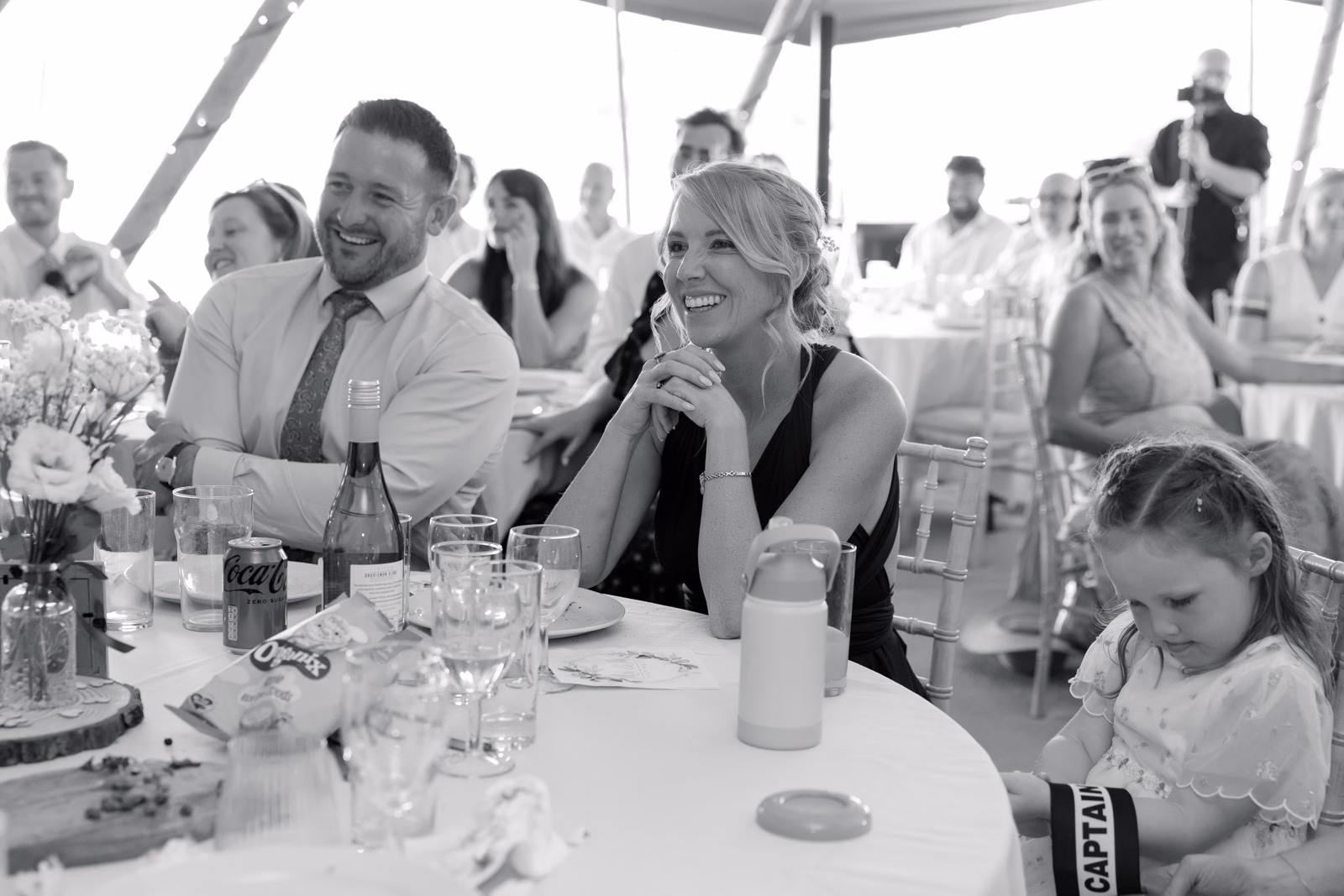 Guests laughing speeches black-and-white at a Taunton farm wedding, photographed by Tanya Bogdan Photography