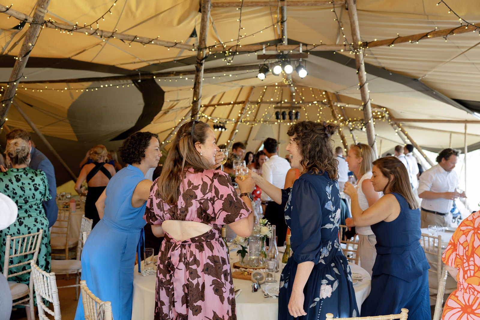 Guests chatting reception tipi at a family farm wedding in Taunton