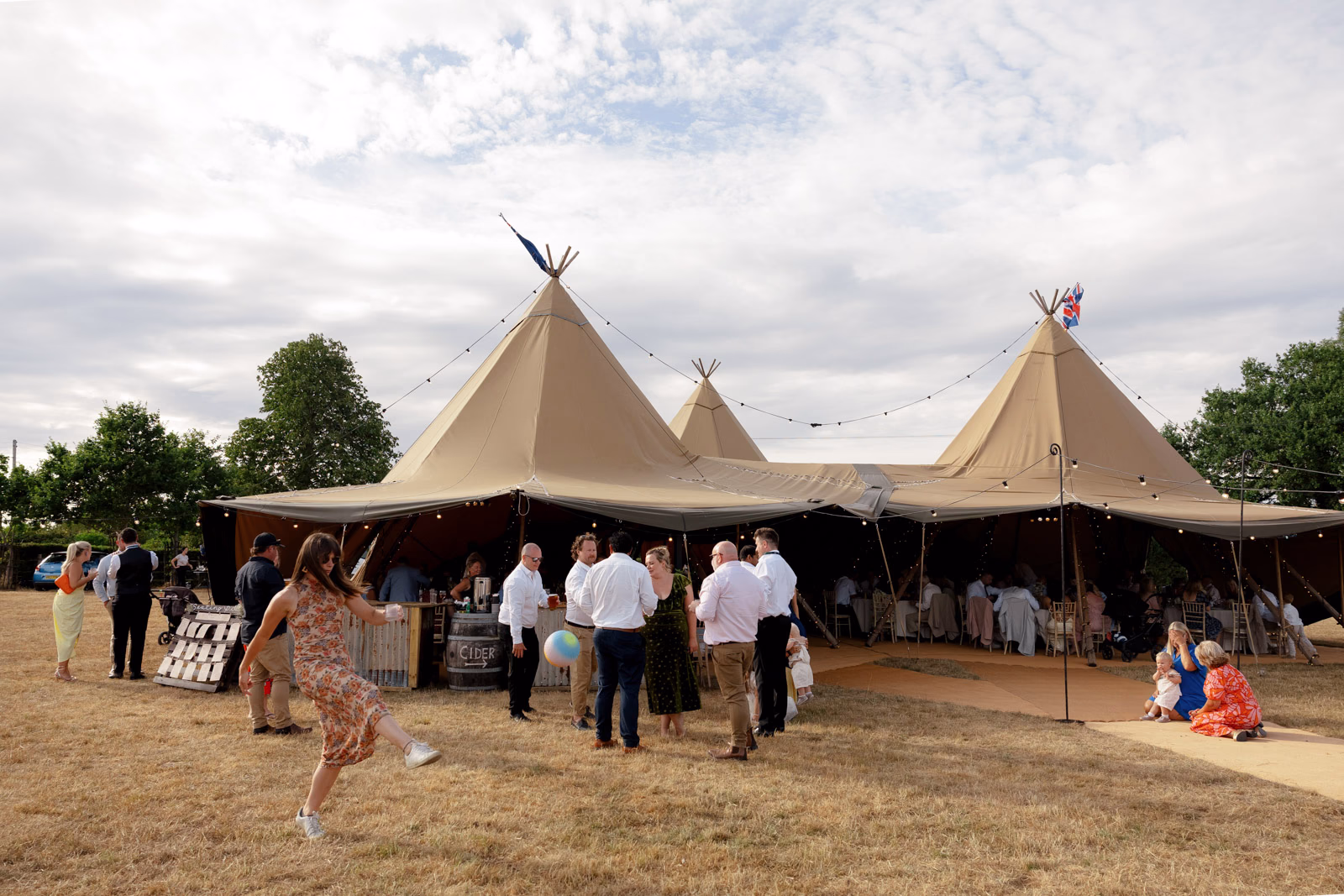 Tipi evening guests on lawn at a countryside wedding in Taunton, Somerset