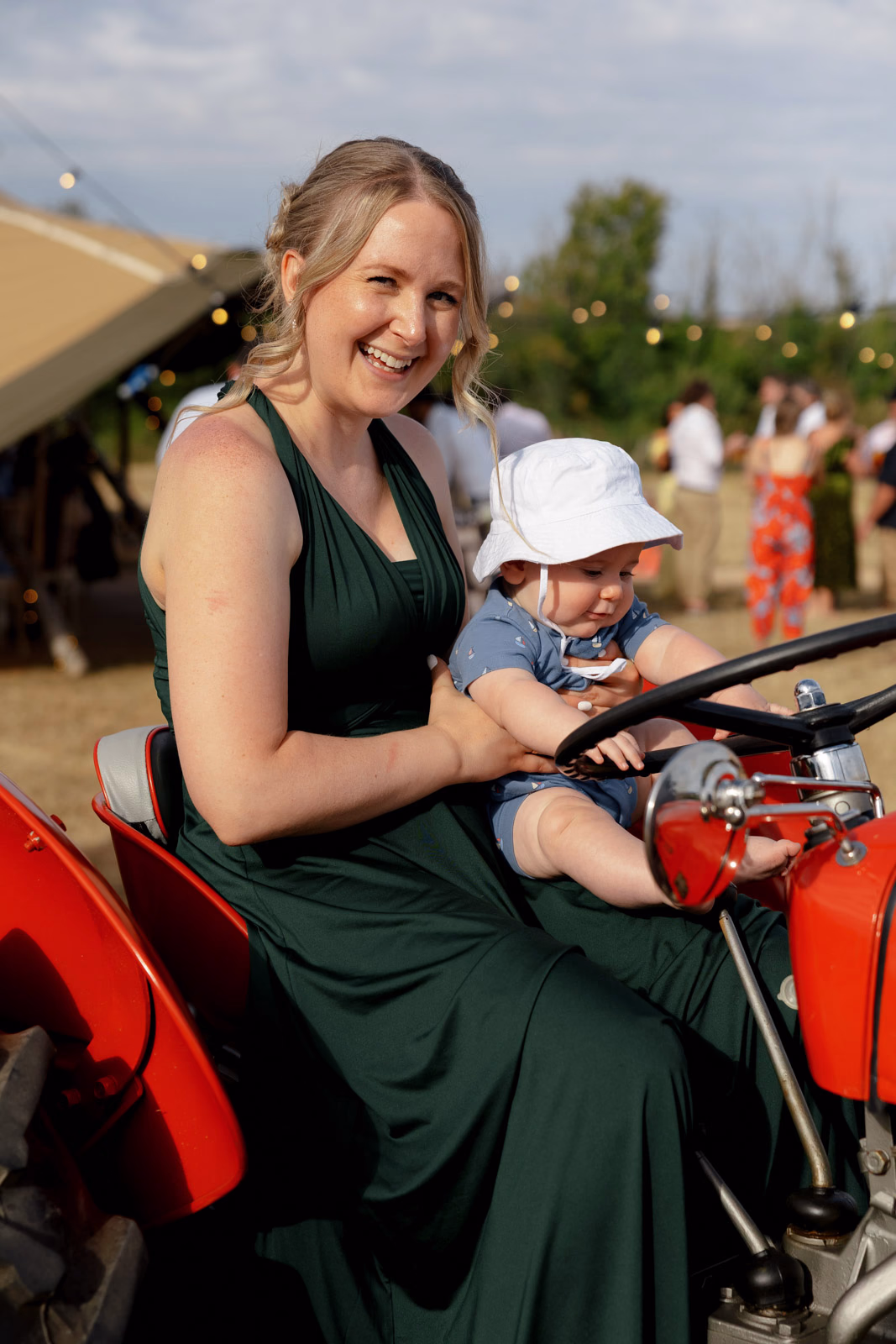 Bridesmaid with baby on tractor at a family farm wedding in Taunton