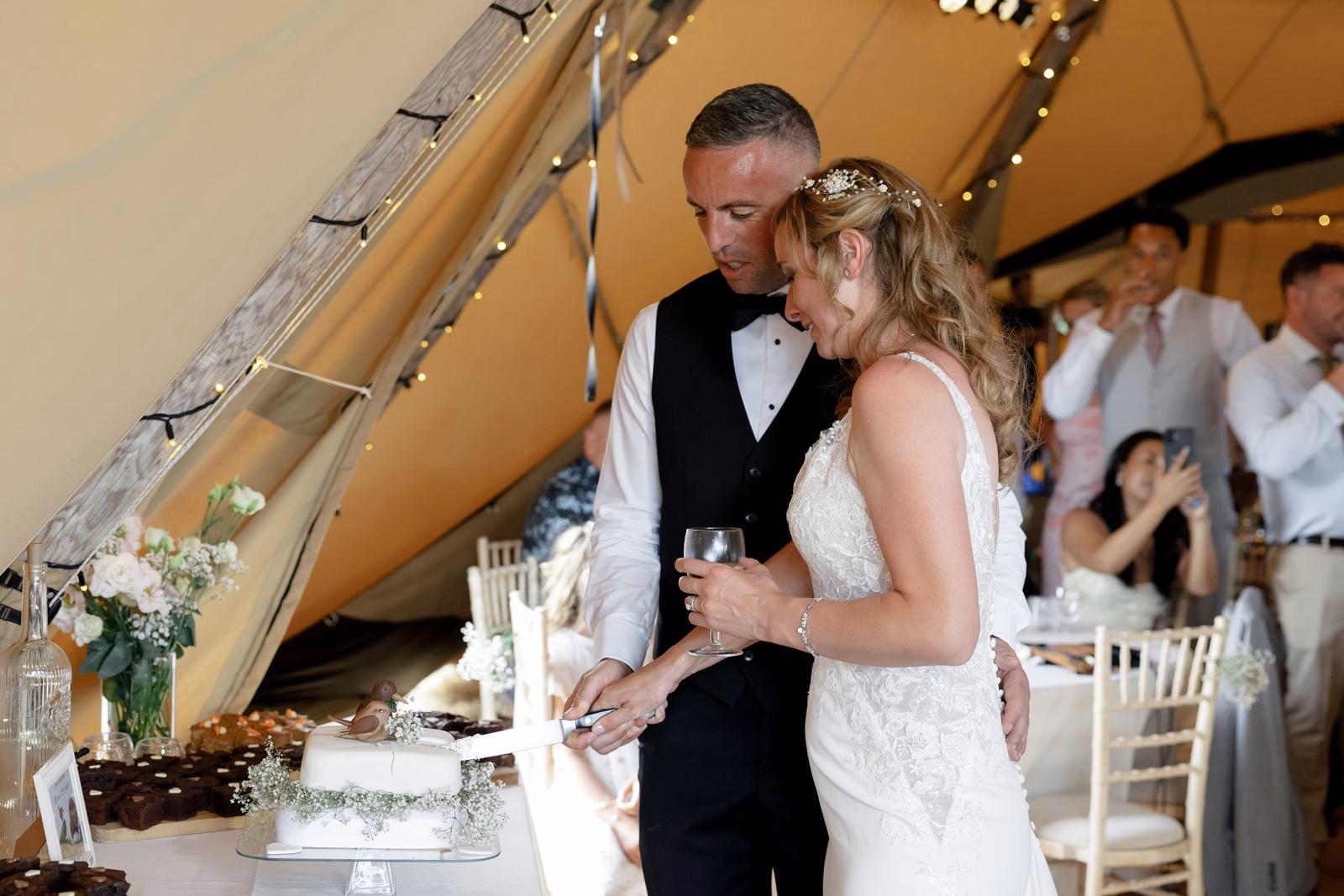 Bride and groom cake cutting tipi at a family farm wedding in Taunton