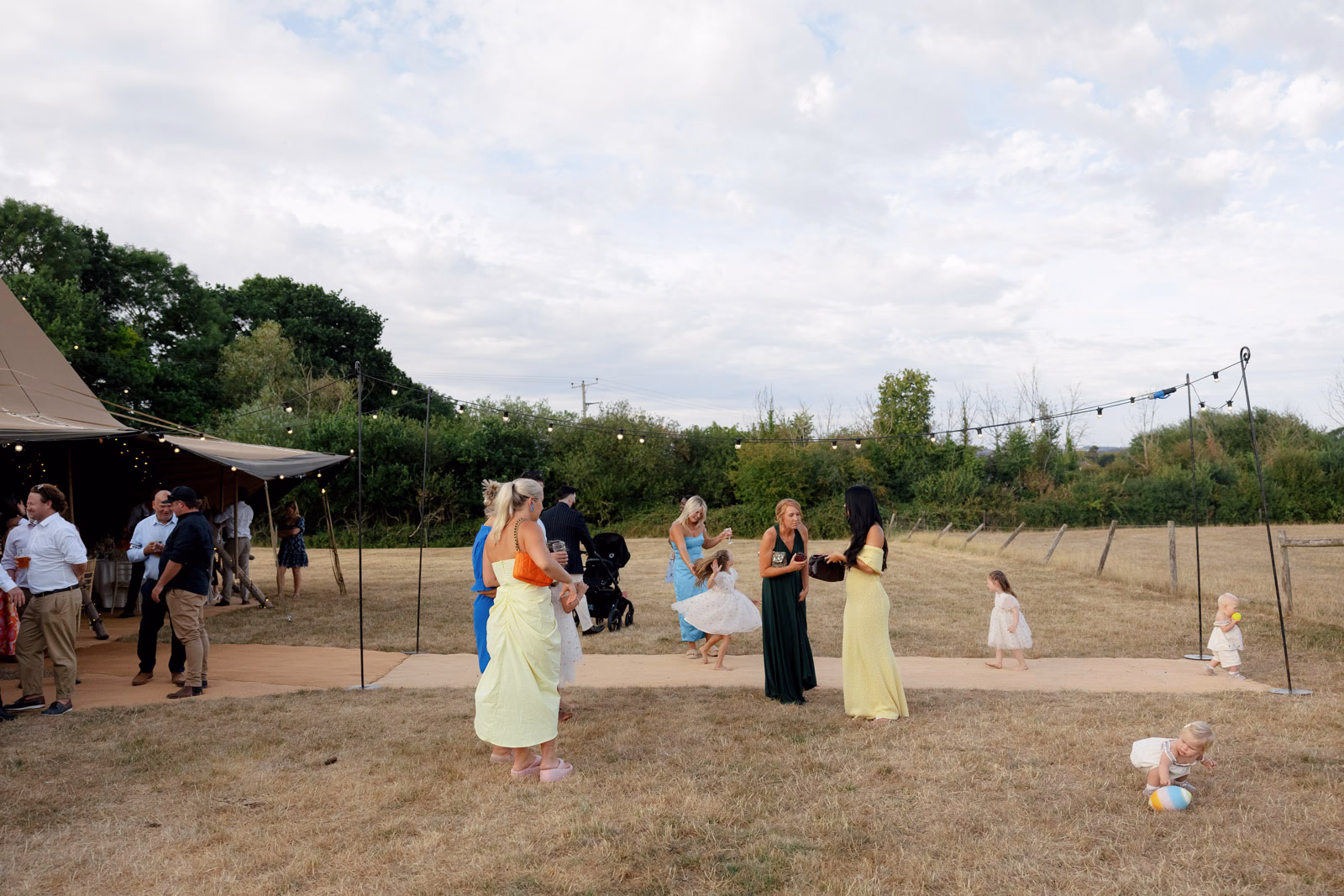 Guests playing in field evening at a family farm wedding in Taunton