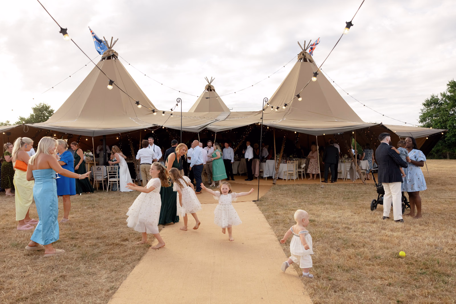 Children playing tipi entrance at a family farm wedding in Taunton