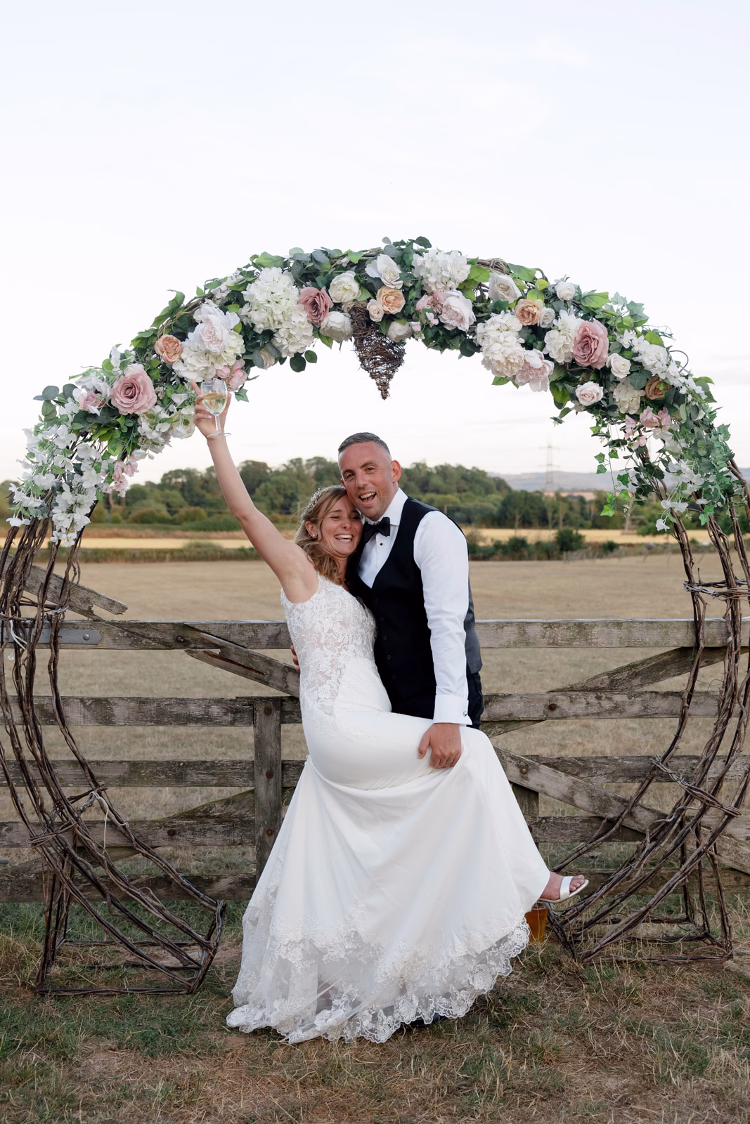 Bride and groom floral arch sunset at a family farm wedding in Taunton