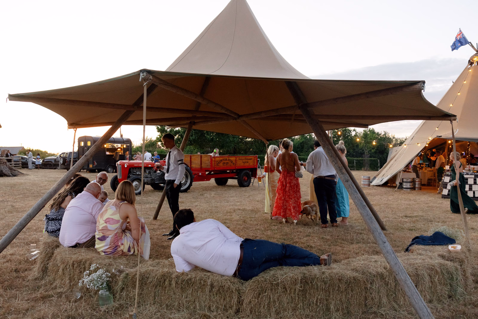 Guest relaxing on hay bales dusk at a countryside wedding in Taunton, Somerset